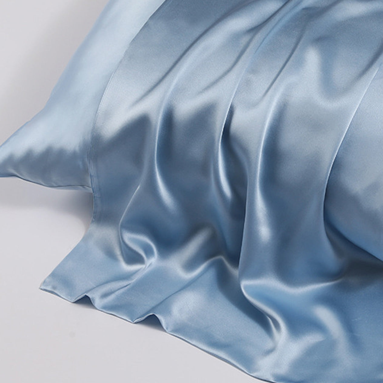 Close-up shot of ohmysilk Silver Blue 22 momme mulberry silk pillowcase with a secure envelope closure, showing natural silk texture and soft wrinkles.